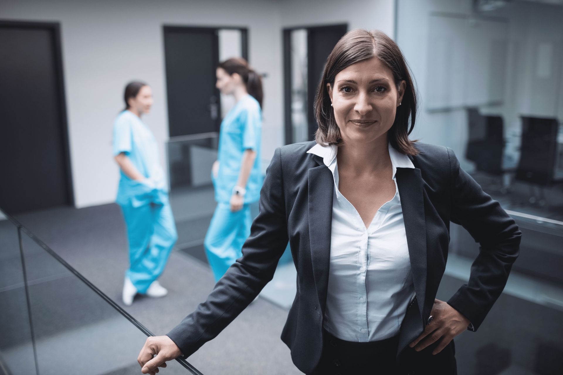 Nurse CEO in business attire with nursing staff in background